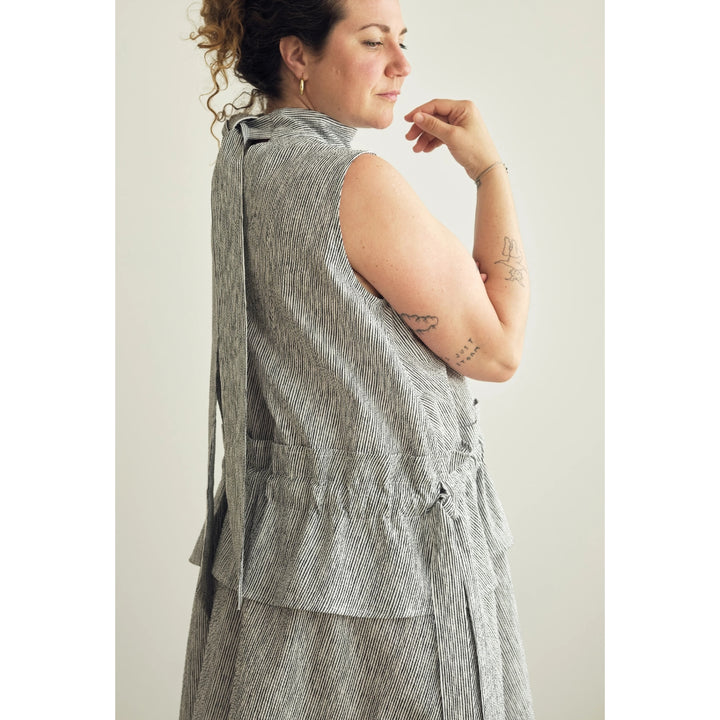 A woman shown from the back wearing a sleeveless gray textured vest with a tie waist, against a plain light background.