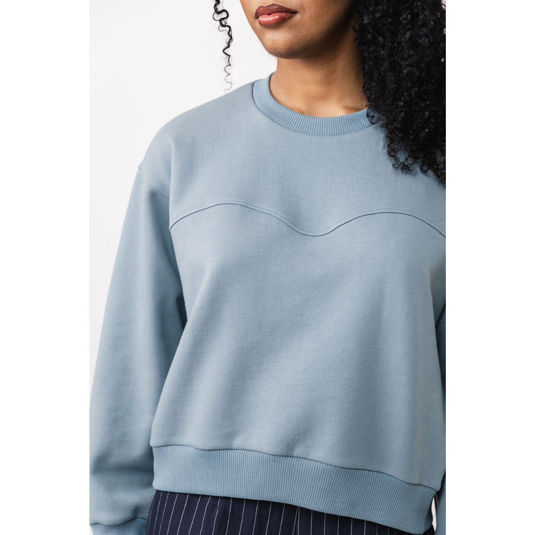 Light blue sweatshirt worn by a person on a white background