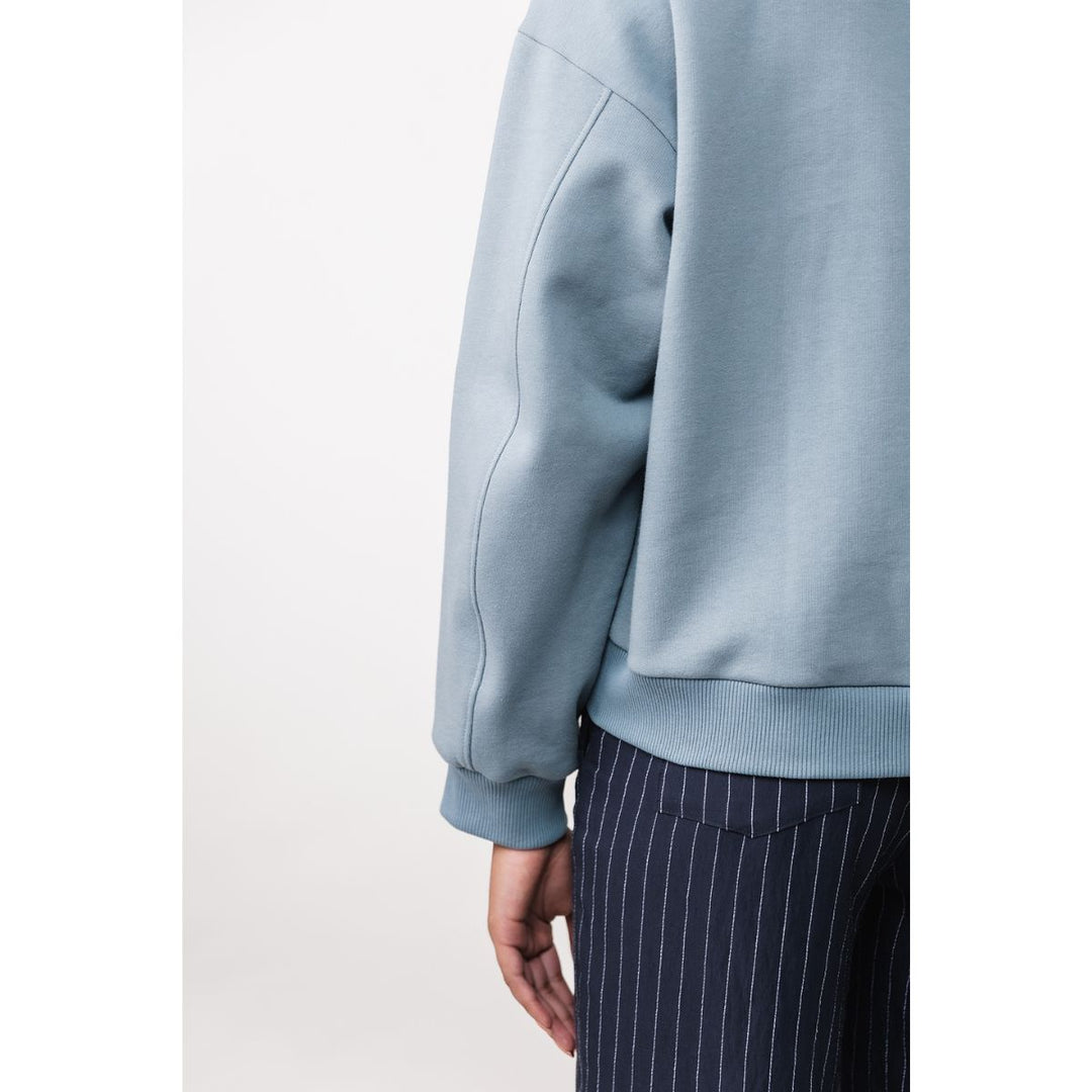 Light blue sweatshirt worn by a person on a white background