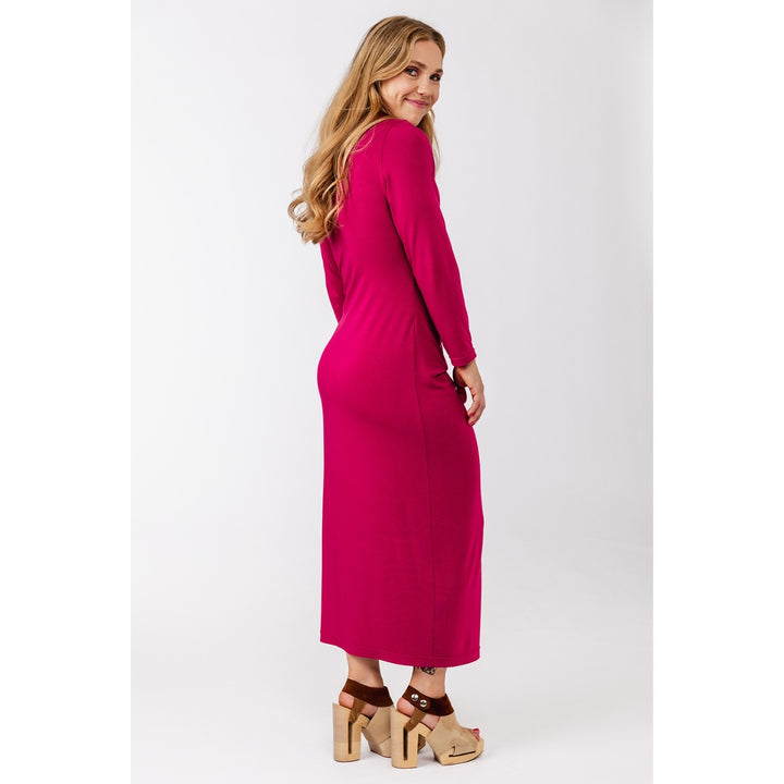 A woman modeling a long-sleeve, knee-length magenta maxi dress, shown from a side-back angle against a plain light gray studio background.