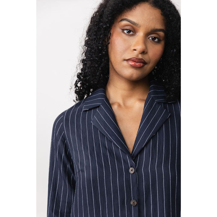 Woman wearing a navy pinstripe shirt on a white background