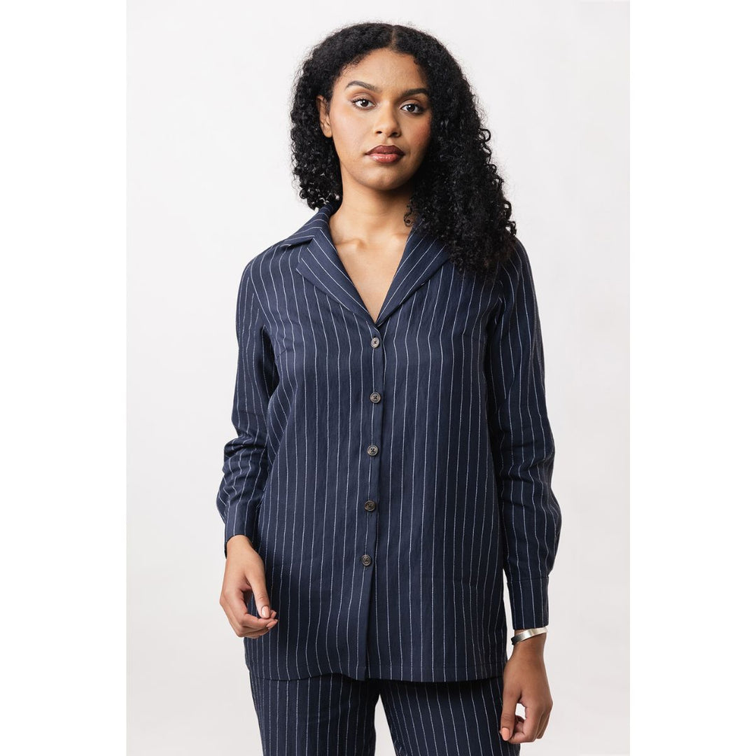 Woman wearing a navy pinstripe shirt with a white background