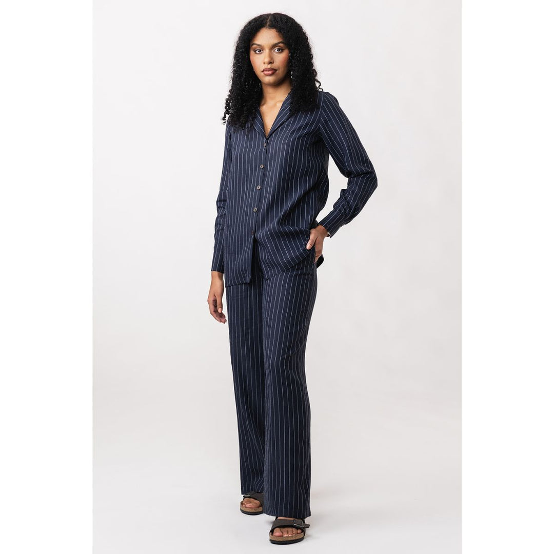 Woman wearing a navy pinstripe shirt and pants on a white background
