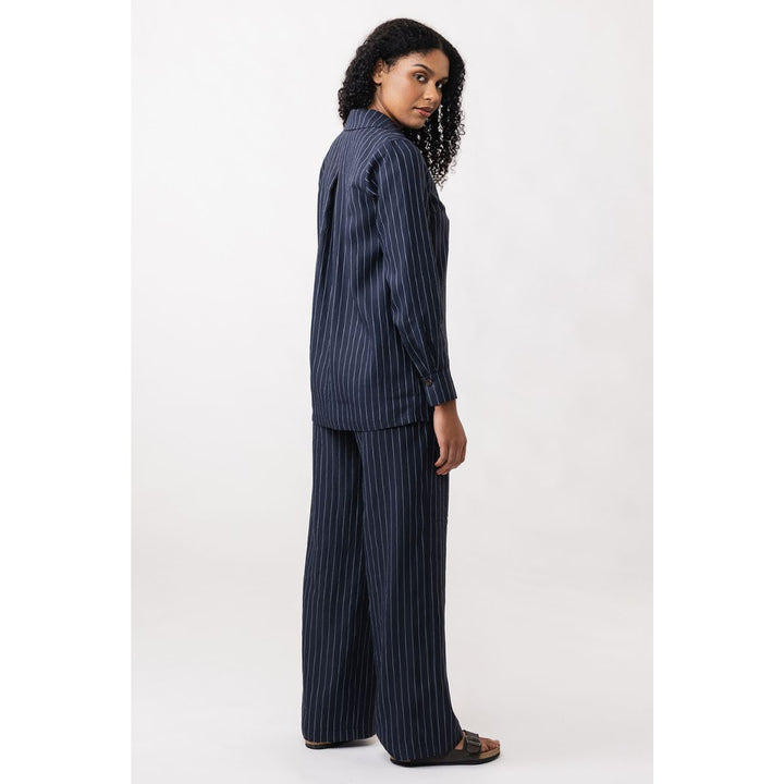 Woman wearing a navy pinstripe shirt and trousers on a white background