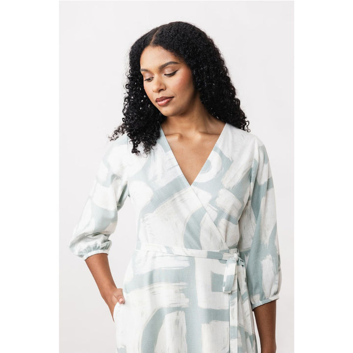 Woman wearing a light-colored patterned dress against a white background