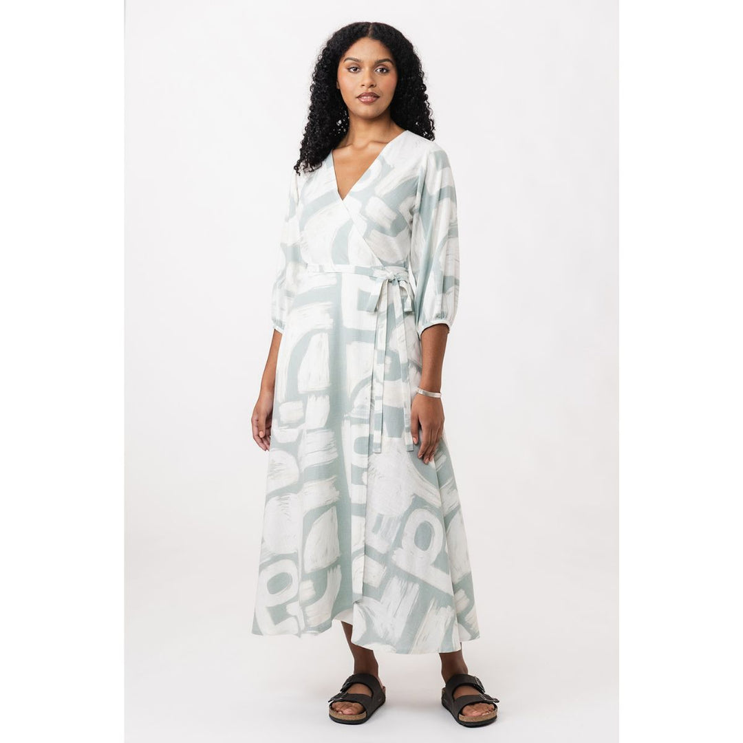 Woman wearing a long, light-colored dress with abstract patterns on a white background