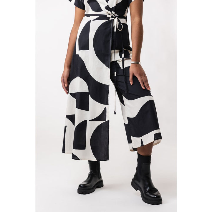 Person wearing a black and white patterned dress with wide-leg pants on a white background