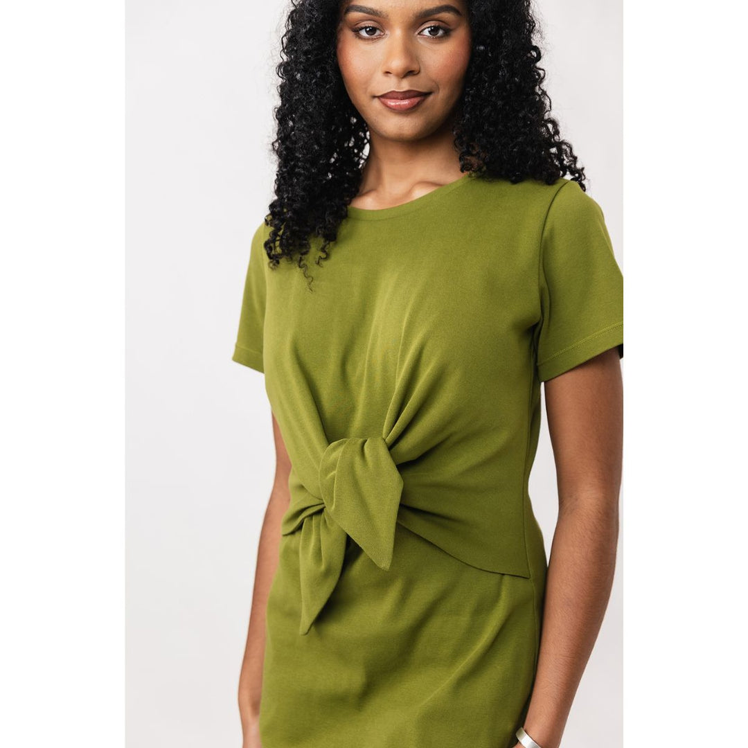 Woman wearing a green dress with a knot detail on a white background