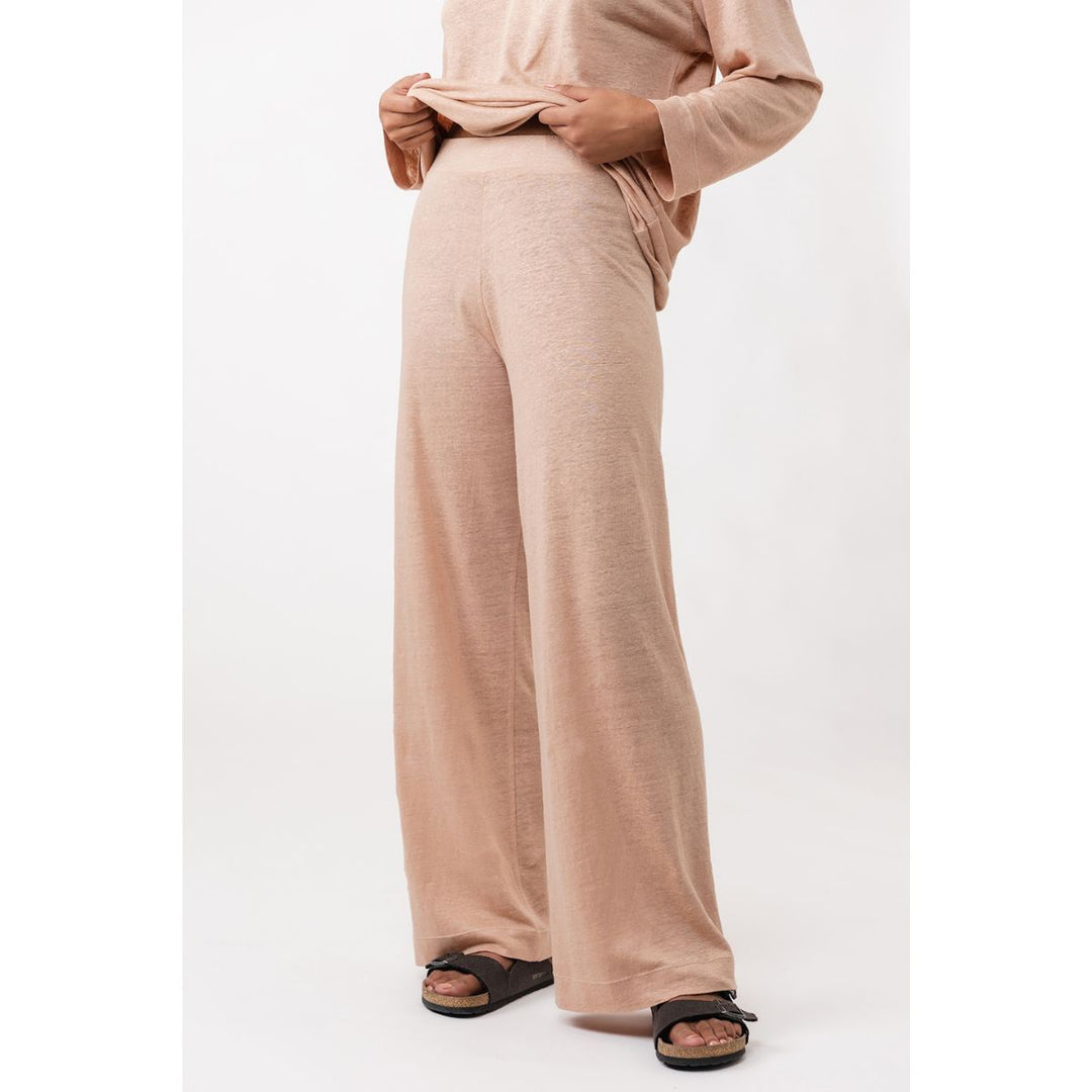 Person wearing a beige outfit with wide-leg pants on a white background