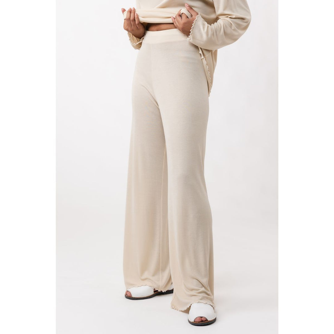 Person wearing beige pants and a matching top on a white background