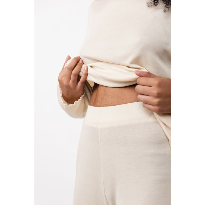 Close-up of a person wearing a cream-colored outfit with a plain background