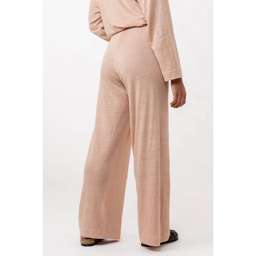 Person wearing a beige outfit with wide-leg pants on a white background