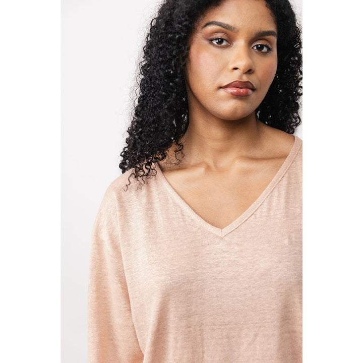 Woman wearing a light pink V-neck top against a white background