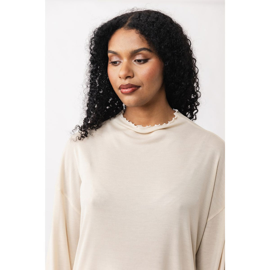 Woman wearing a beige sweater against a white background
