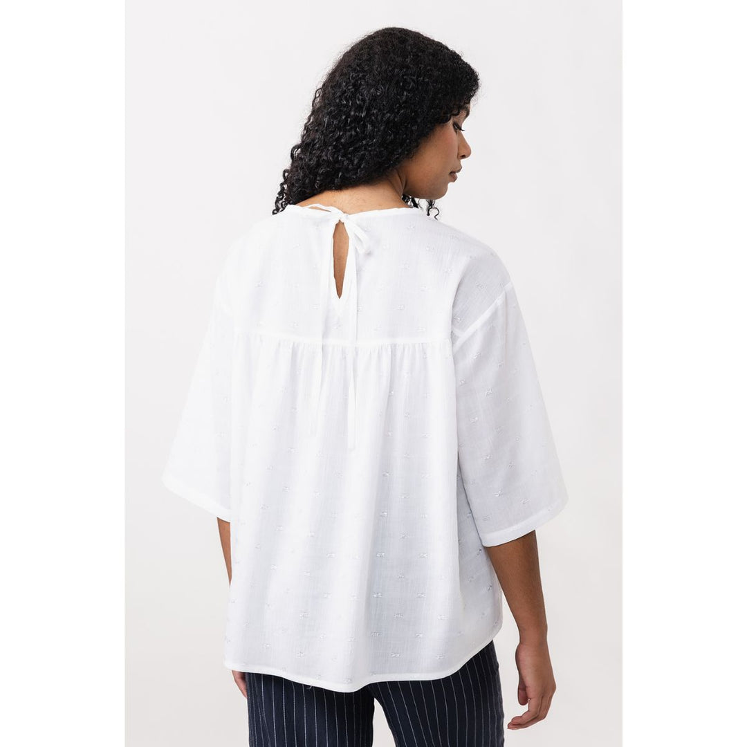 Woman wearing a white blouse with a plain background