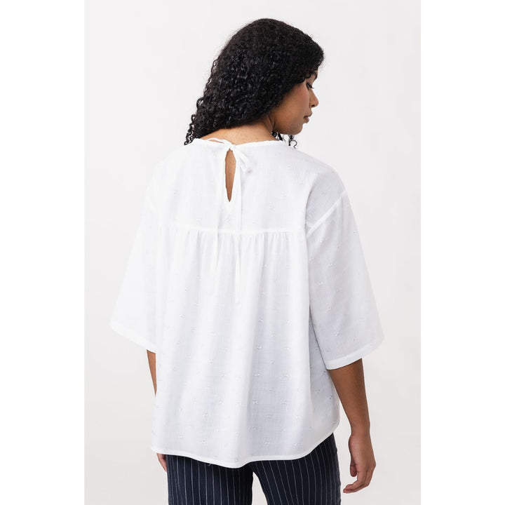 Woman wearing a white blouse with a plain background