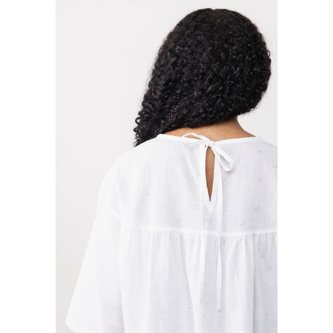 Person wearing a white dress with a plain background