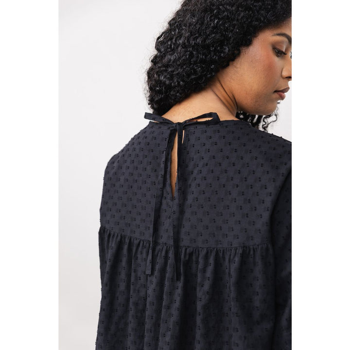 Woman wearing a black patterned dress with a white background