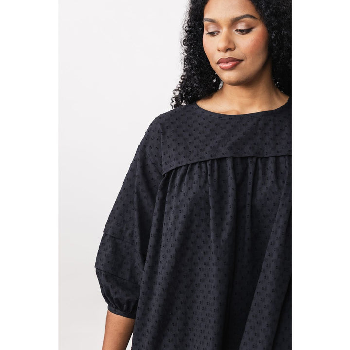 Woman wearing a black patterned dress against a white background