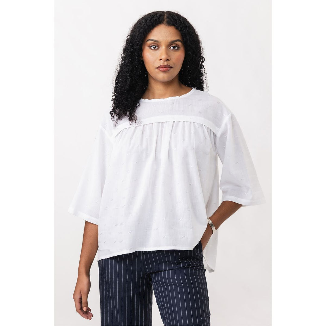 Woman wearing a white blouse and navy pinstripe pants on a white background