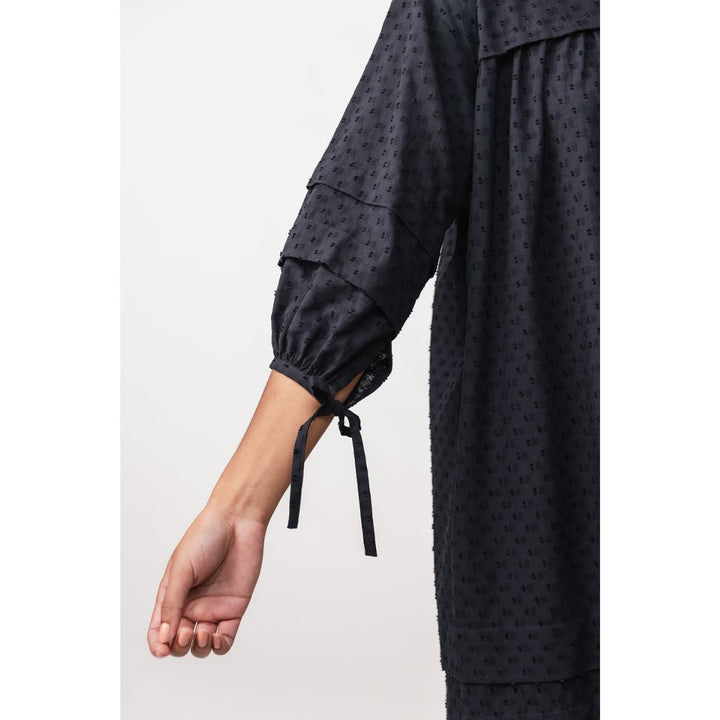 Black textured garment with long sleeves and a white background