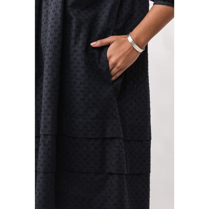 Black patterned dress with a hand in a pocket on a white background