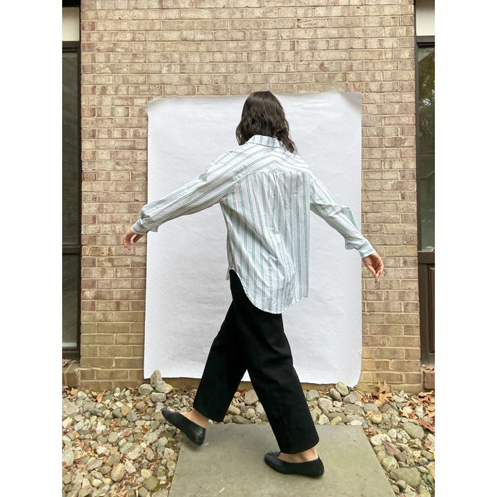 Person standing in front of a white sheet against a brick wall