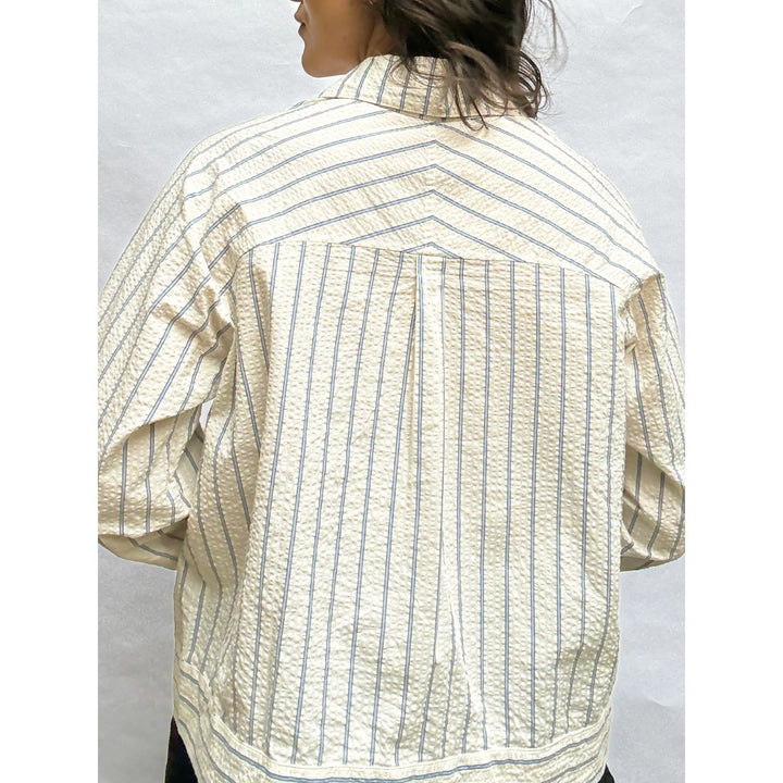 Person wearing a patterned shirt with short sleeves on a plain background