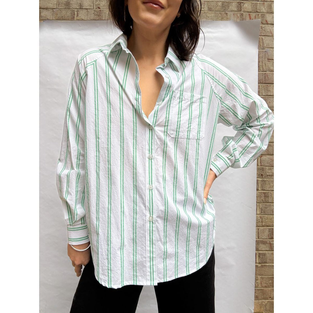 Woman wearing a white shirt with green stripes against a neutral background