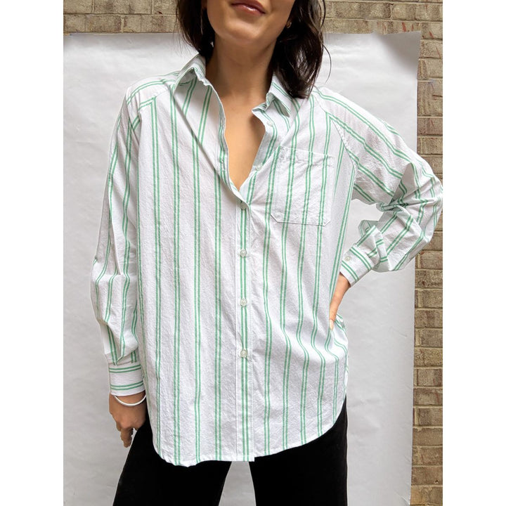 Woman wearing a white shirt with green stripes against a neutral background