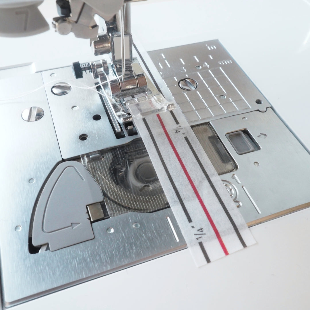 Close-up of a sewing machine needle plate with measurement guide on a white background