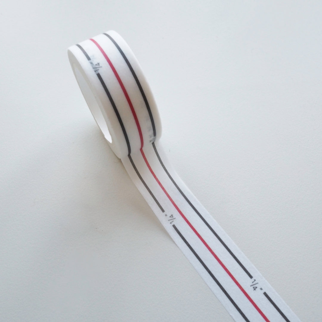 Roll of white tape with red and black stripes on a light gray background