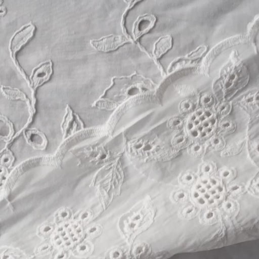 White cotton dressmaking fabric with floral embroidered border and scalloped edge