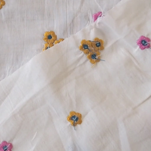 White cotton voile fabric with small colourful embroidered flowers on a white background