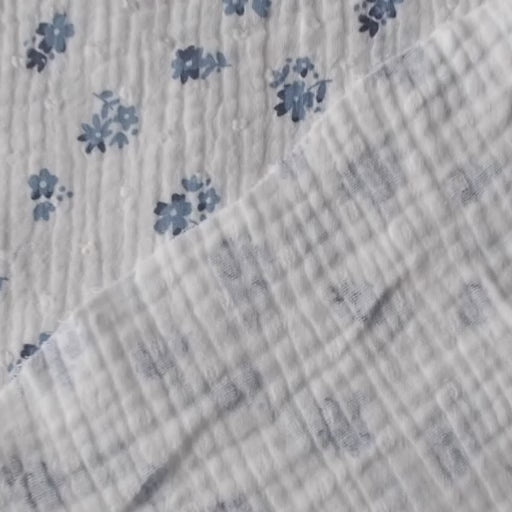 White cotton double gauze dressmaking fabric with dobby texture and ditsy blue floral pattern