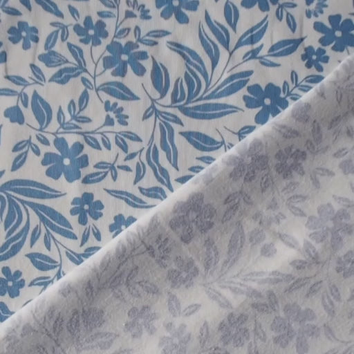 Stretch cotton jersey dressmaking fabric with blue floral pattern on a white background