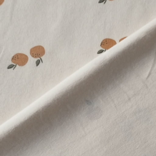 Ecru stretch cotton jersey dressmaking fabric with orange motifs