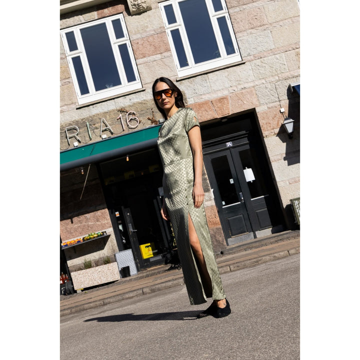 Woman in a green dress standing on a street with a building in the background