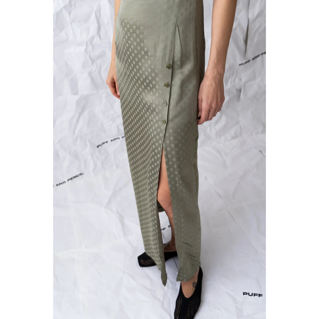 Person wearing a long green dress with a pattern on a white background