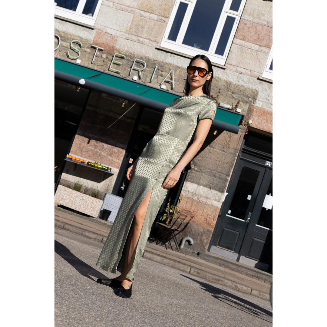 Woman in a green dress standing in front of a building with 'Osteria' sign.