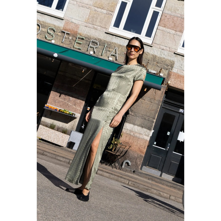 Woman in a green dress standing in front of a building with 'Osteria' sign.