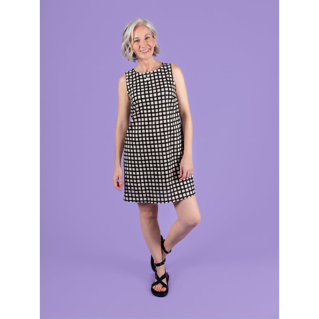 Woman wearing a black and white checkered dress against a purple background