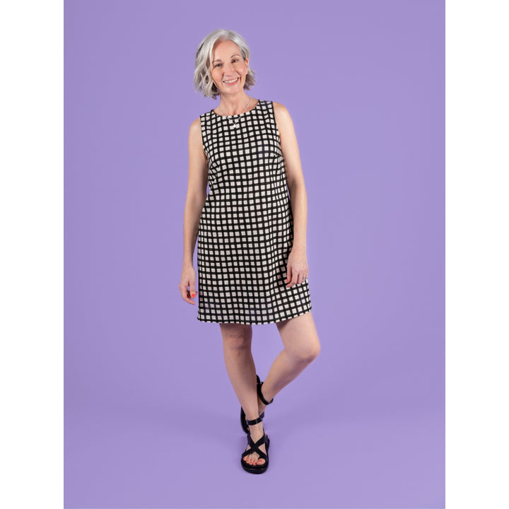 Woman wearing a black and white checkered dress against a purple background
