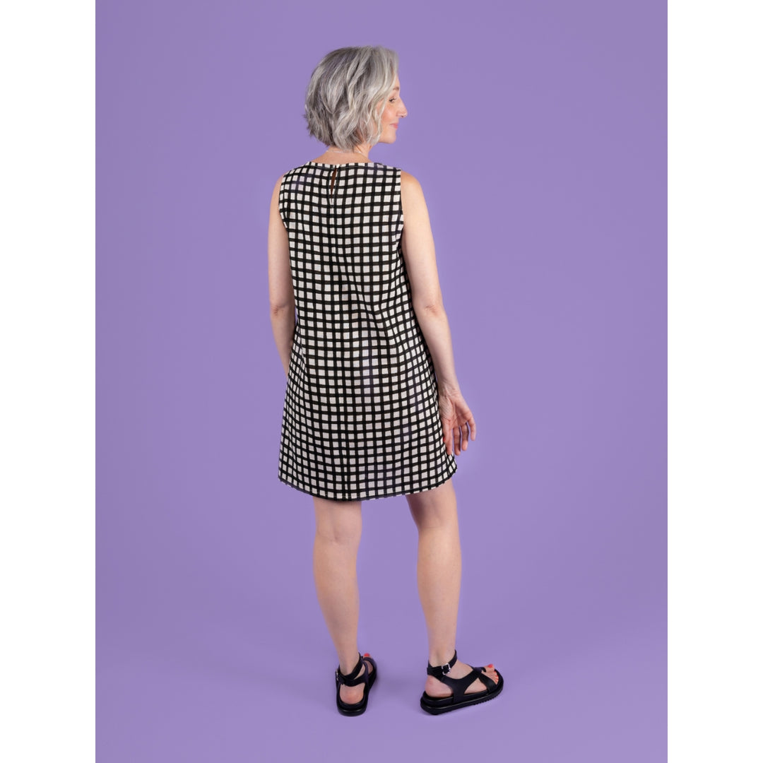 Woman wearing a black and white checkered dress against a purple background