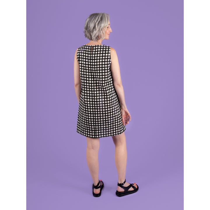 Woman wearing a black and white checkered dress against a purple background
