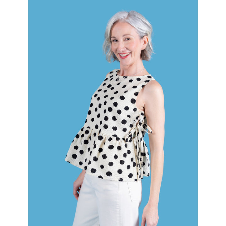 Woman wearing a polka dot blouse against a blue background