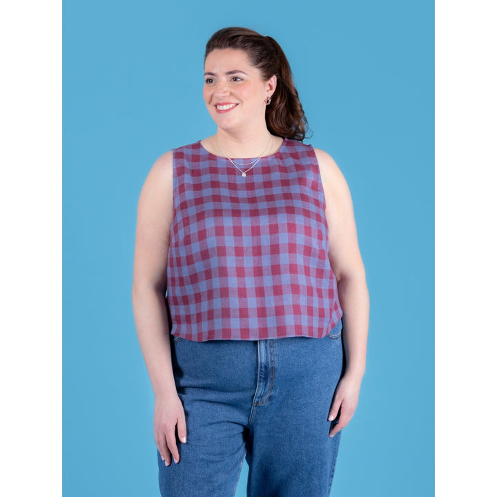 Woman wearing a red and blue checkered sleeveless top against a blue background