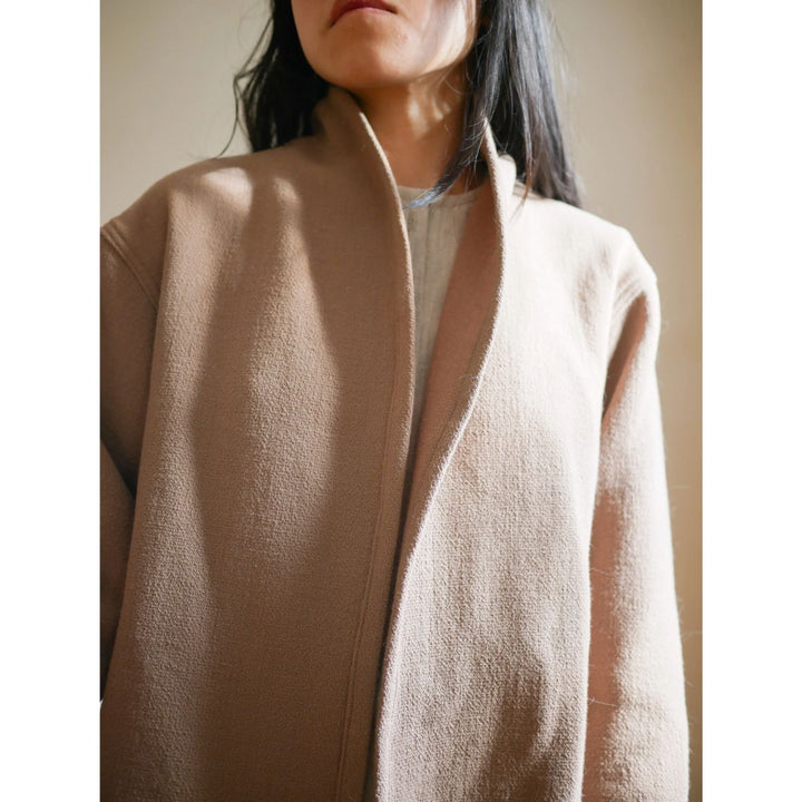 Person wearing a beige cardigan with a neutral background