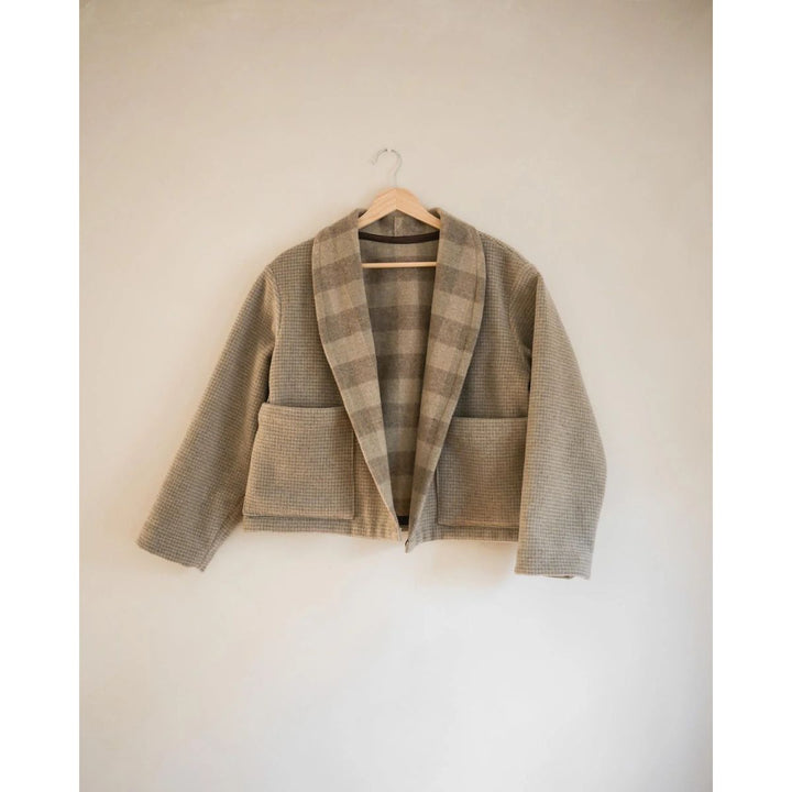 Plaid blazer on a hanger against a plain background