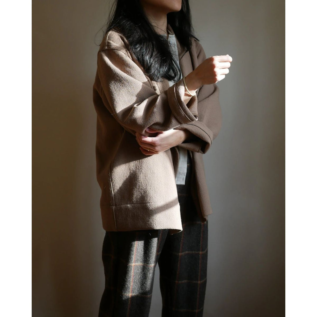 Person wearing a beige coat with a neutral background